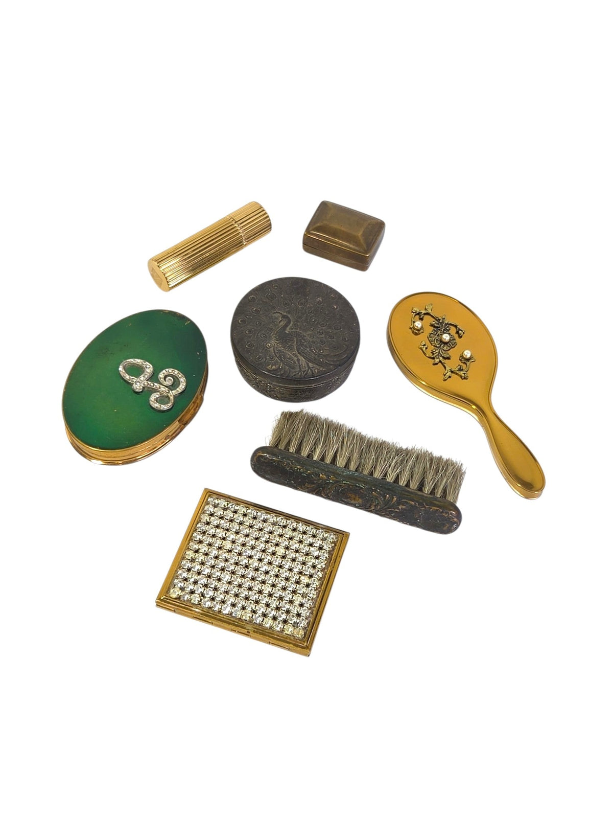 Vintage powder compacts with a green monogram lid and a pave rhinestone lid, beside a gold-tone hand mirror and vanity pieces