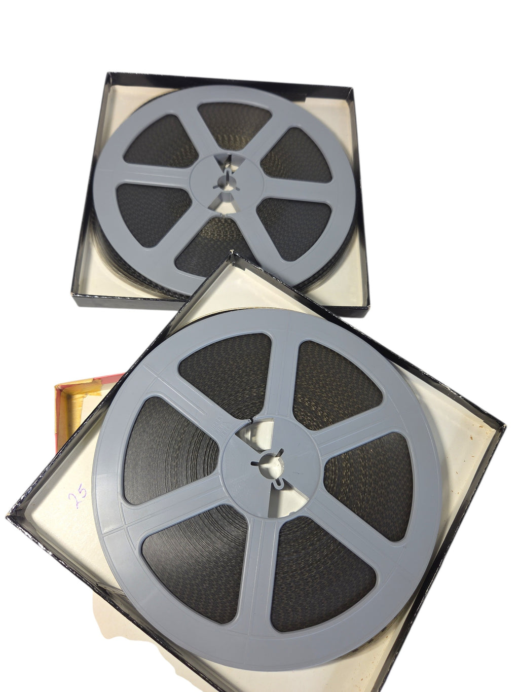 Two Blackhawk Super 8 films on gray plastic reels in their open boxes, with a penned number inside one box