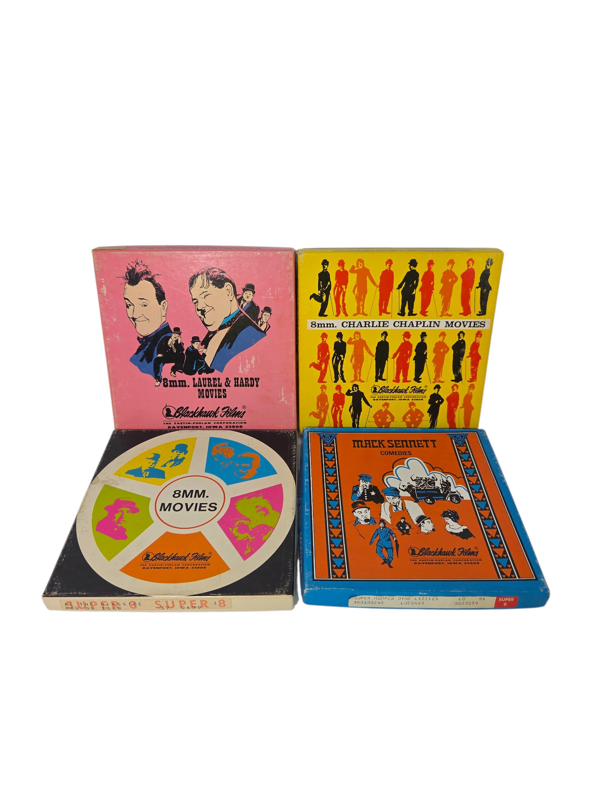 Four vintage Blackhawk Films Super 8 home movie boxes on white: pink Laurel & Hardy, yellow Charlie Chaplin, 8mm Movies reel design and orange Mack Sennett Comedies