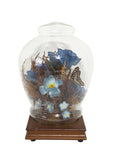 Vintage ginger jar shaped glass dome cloche on white with blue silk roses, dried flowers and a butterfly on a square wood base