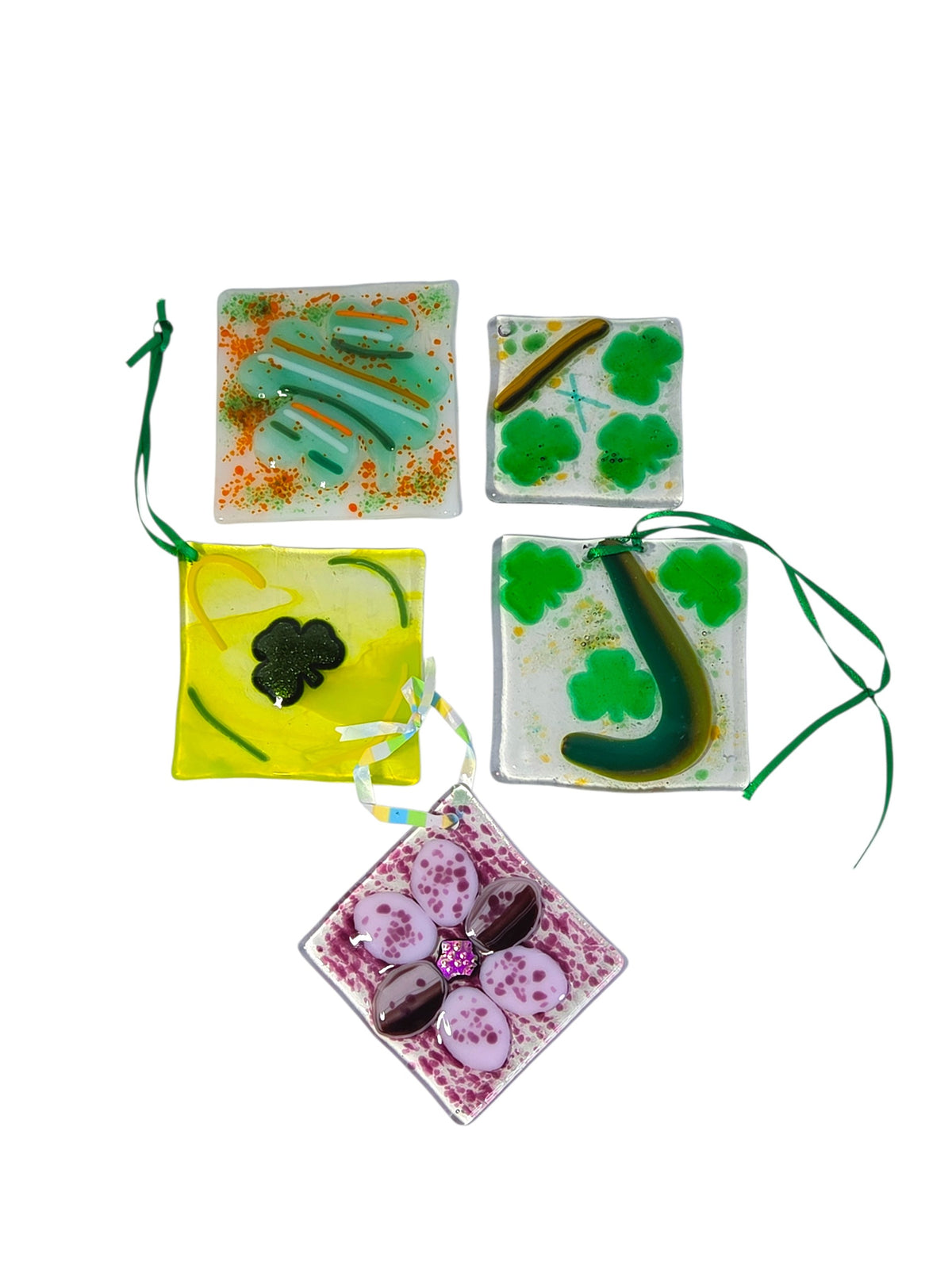 Lot of five handmade fused glass suncatcher ornaments on white: four Irish shamrock squares and one purple flower