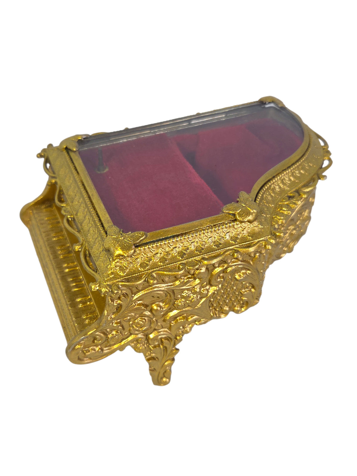 Gold-tone piano jewelry box from the keyboard side with light glare on the glass lid
