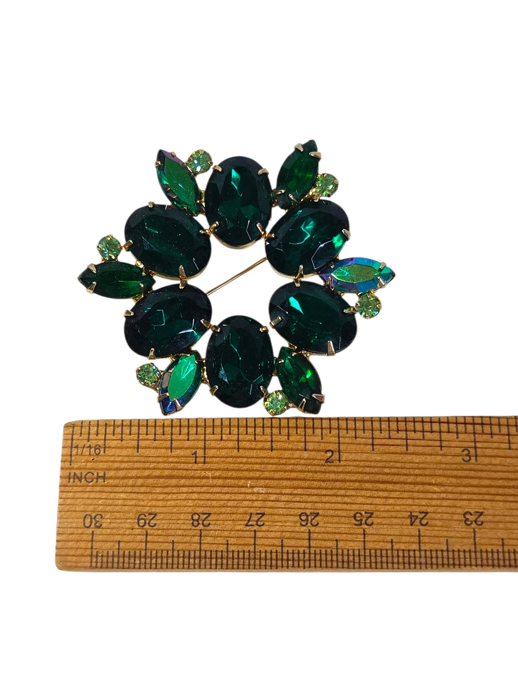 Emerald green rhinestone wreath brooch beside a ruler, about 2 1/2 inches across