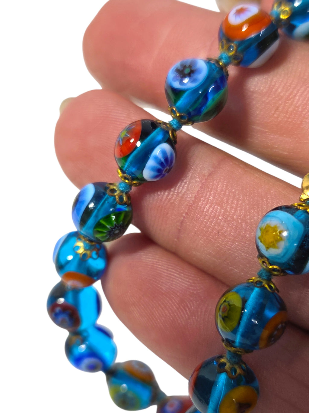 Millefiori glass bead bracelet showing star, flower and bullseye canes between gold-tone filigree bead caps