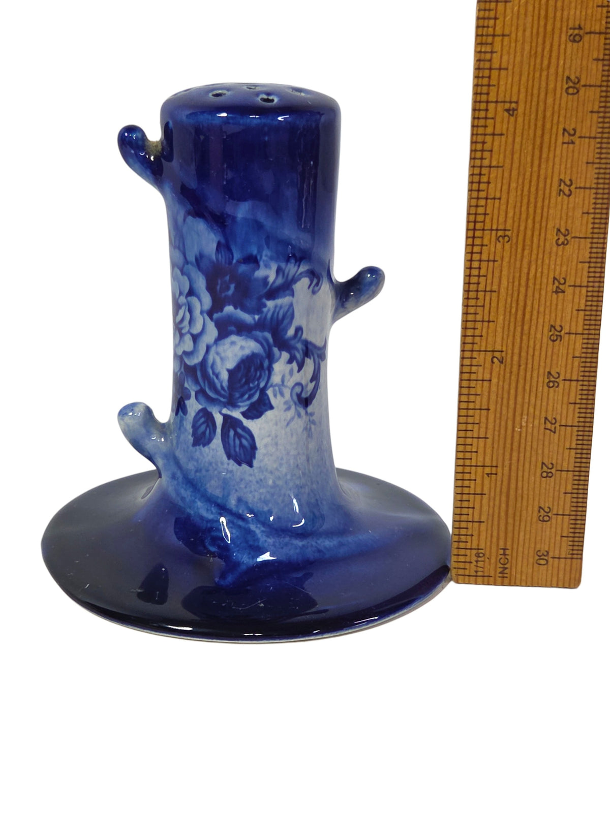 Unglazed open bottom of the hatpin holder with a faint blue stamp and rust-colored stains, held in hand