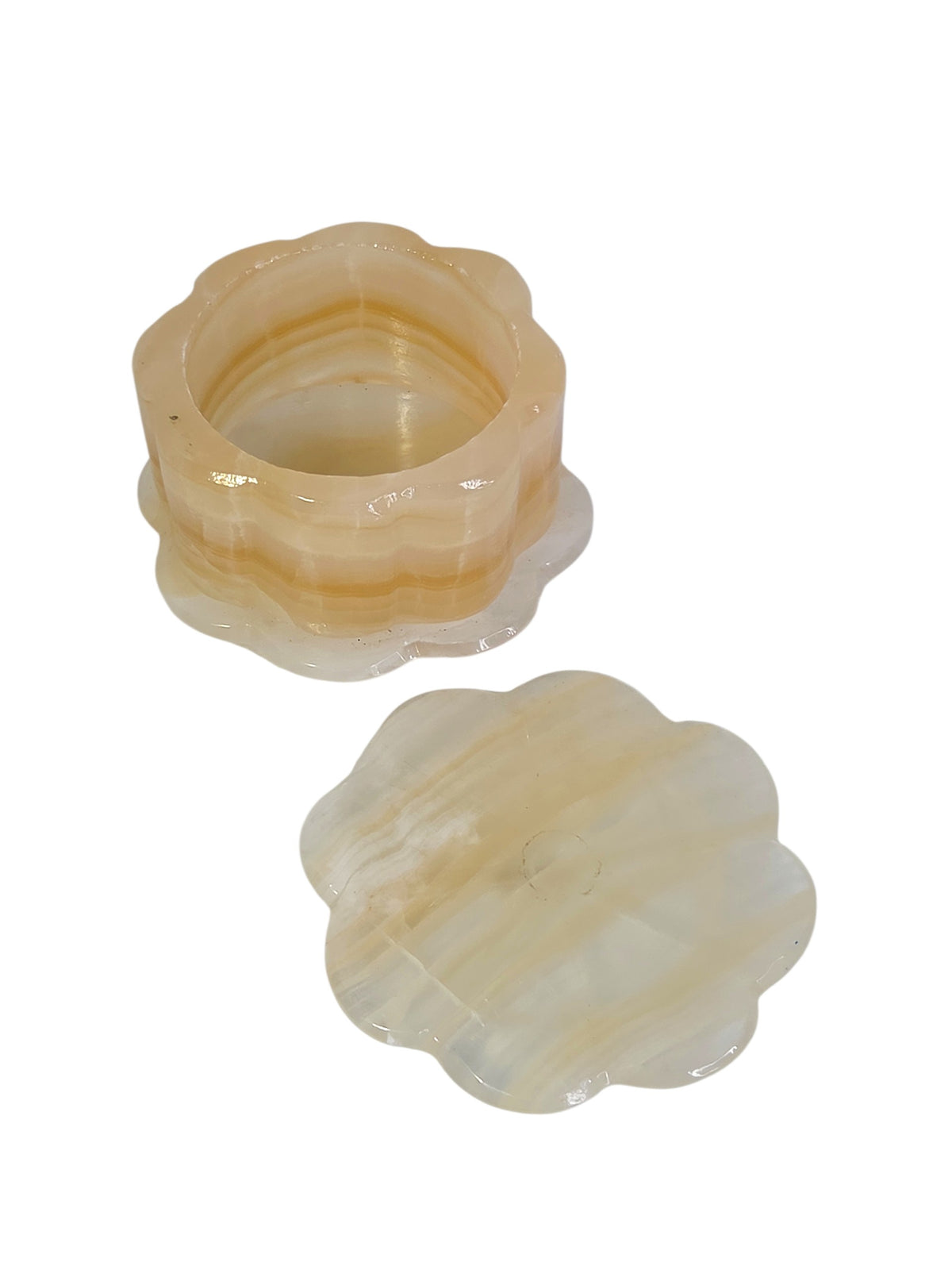 Onyx trinket box turned upside down showing the scalloped base and three peg feet, one darker, with the lid underside beside it