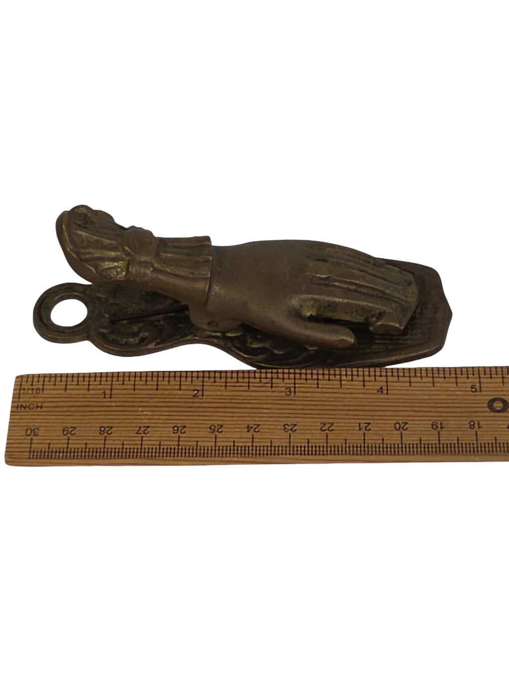 Brass hand clip held open with a finger, showing the spring action and crosshatch back plate