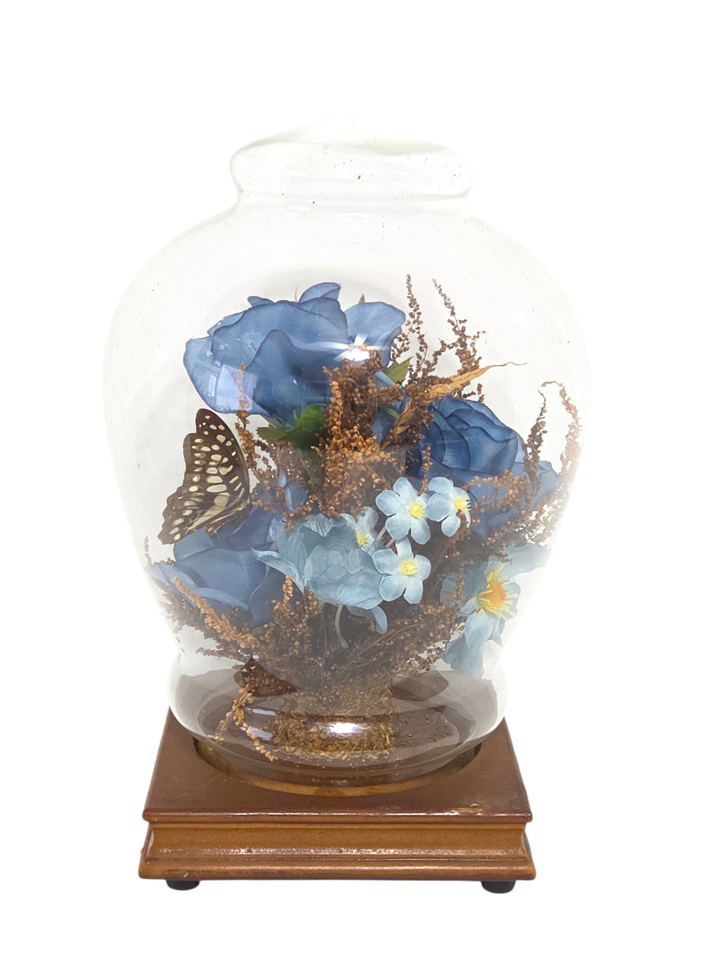 Other side of the glass dome with the butterfly on the left, blue roses and small blue flowers in dried golden brown sprays