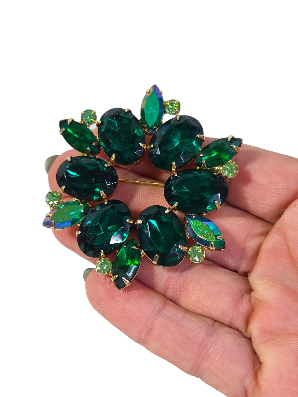 Back of the green rhinestone wreath brooch showing closed gold-tone stone cups, pin stem and catch, unsigned