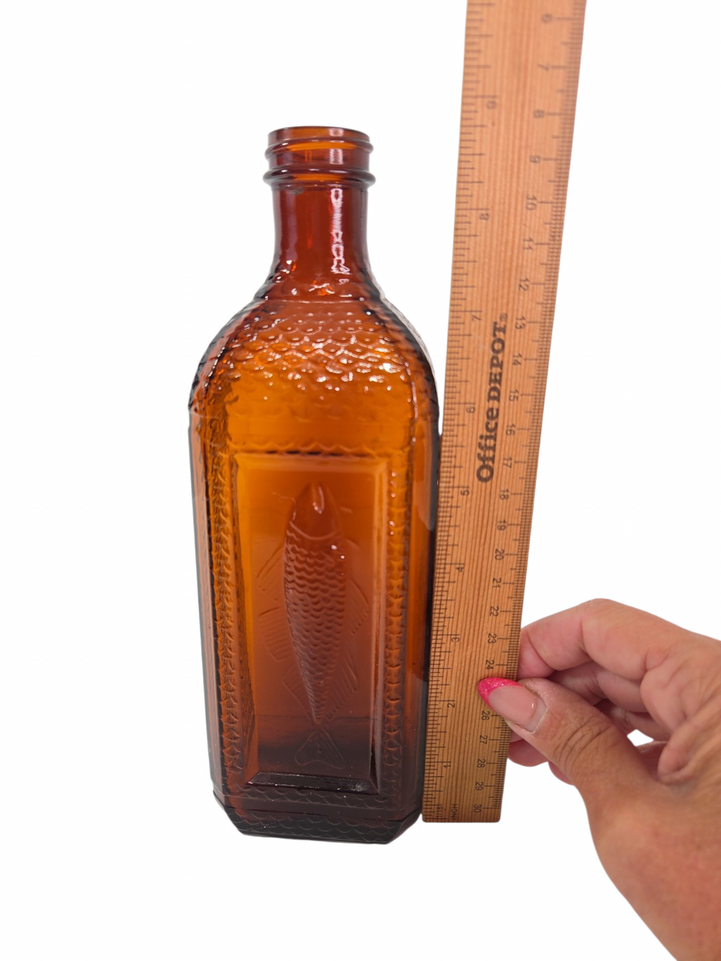 Oddly Darling Vintage amber glass bottle with an embossed fish design and textured scale sides next to a ruler