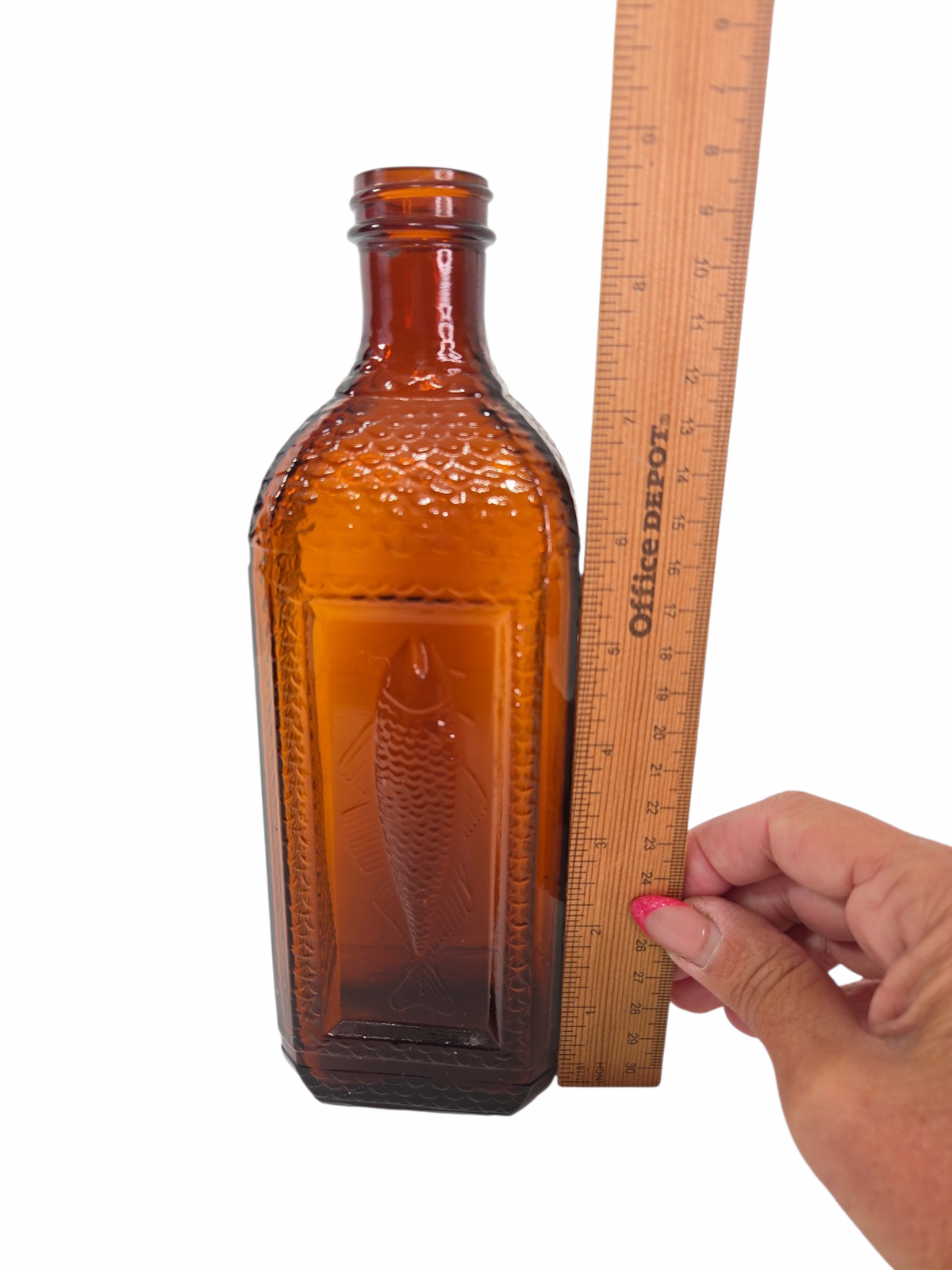 Oddly Darling Vintage amber glass bottle with an embossed fish design and textured scale sides next to a ruler