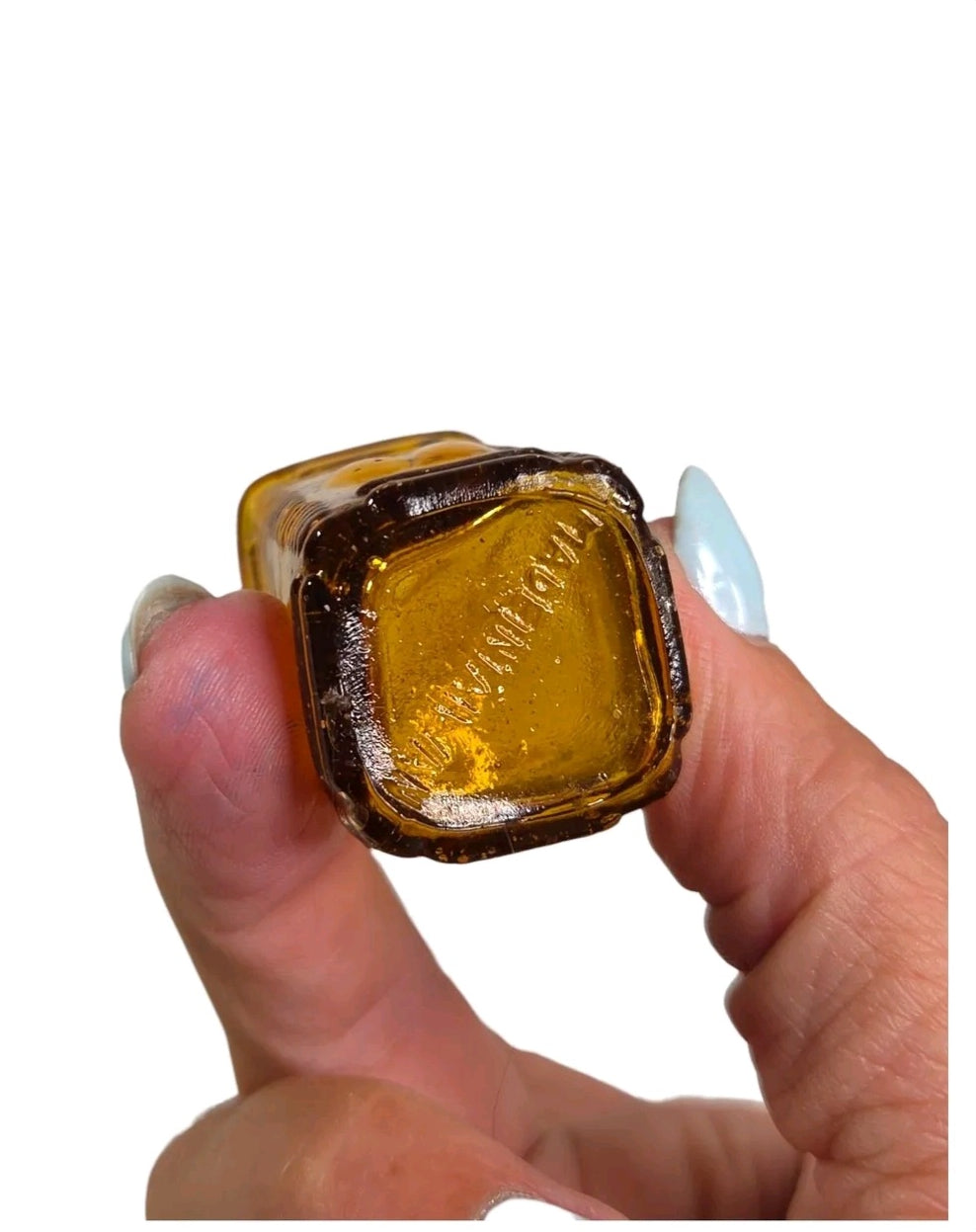 Oddly Darling Vintage miniature square amber glass apothecary bottle base with embossed lettering held in hand