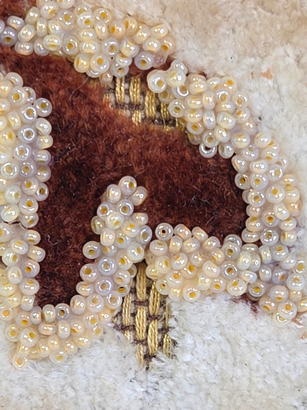 Corner of the beaded panel where a few beads are missing and loose threads show by the ric-rac trim
