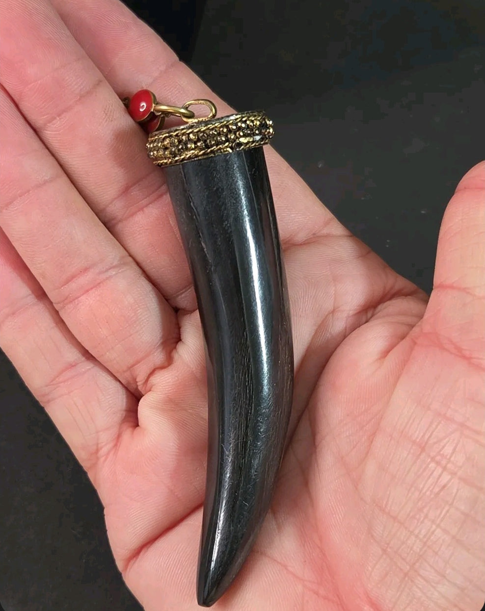 Oddly Darling Vintage black horn tusk pendant with gold-tone textured cap held in a palm