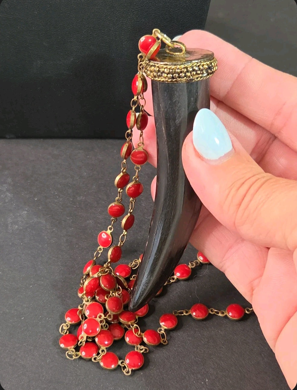 Oddly Darling Vintage long necklace with a black horn tusk pendant, gold-tone cap, and vibrant red enamel beads.