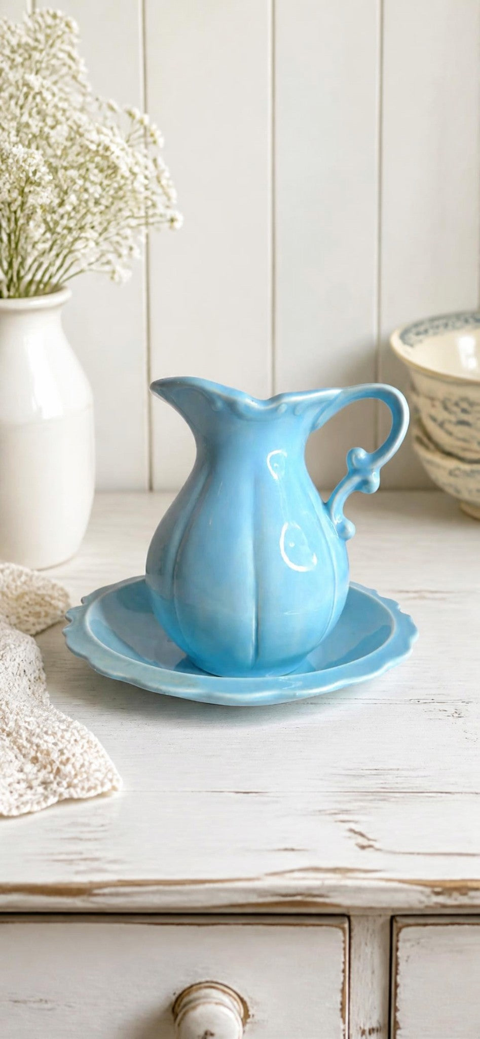 Oddly Darling Vintage sky-blue ceramic pitcher and matching scalloped saucer set on a white rustic wooden table.