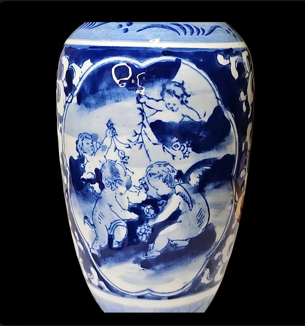 Oddly Darling Vintage blue and white ceramic vase featuring hand-painted cherub motifs and intricate floral scrollwork.