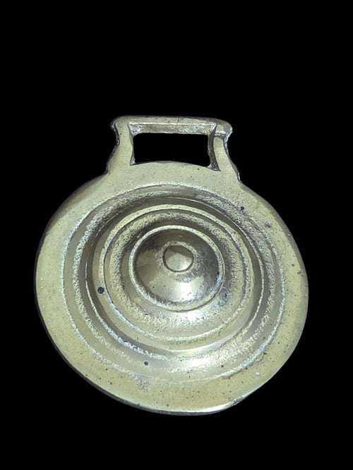 Oddly Darling Vintage brass horse harness medallion with concentric ring design and warm patina on black background