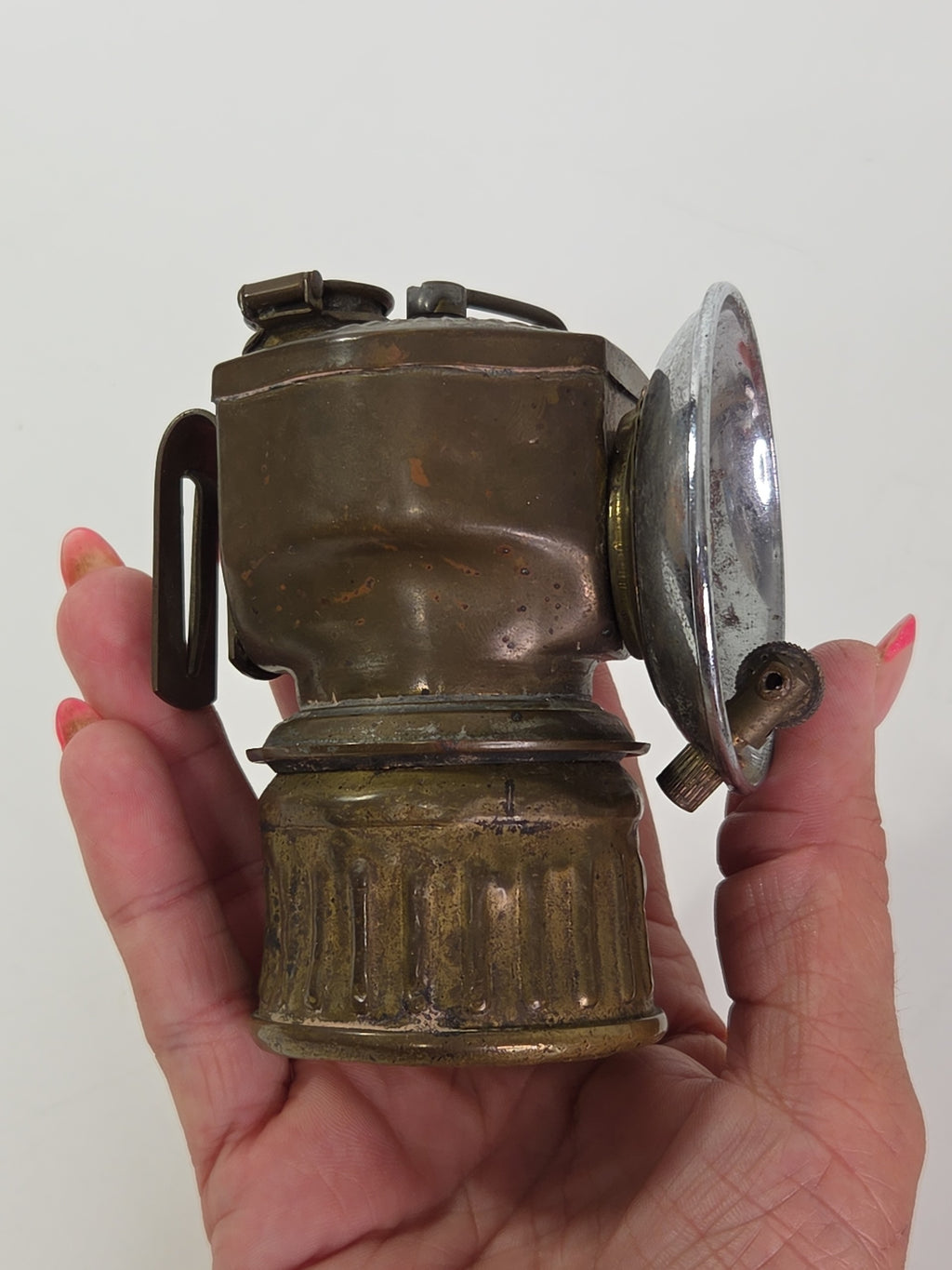 Oddly Darling Vintage antique brass carbide miner lamp with a chrome reflector held in a hand
