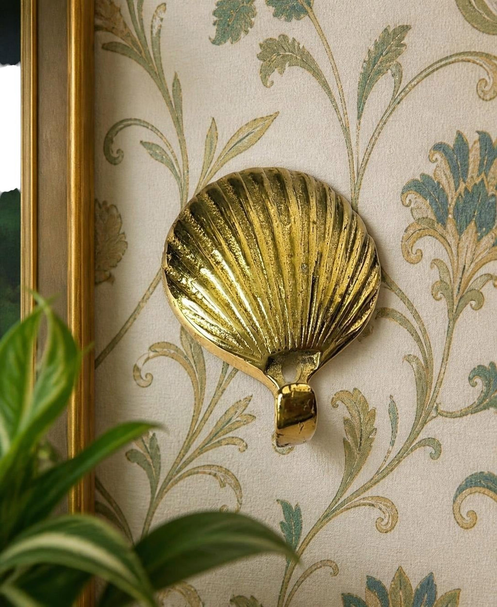 Oddly Darling Vintage brass scallop shell wall hook with a polished gold finish mounted on floral wallpaper