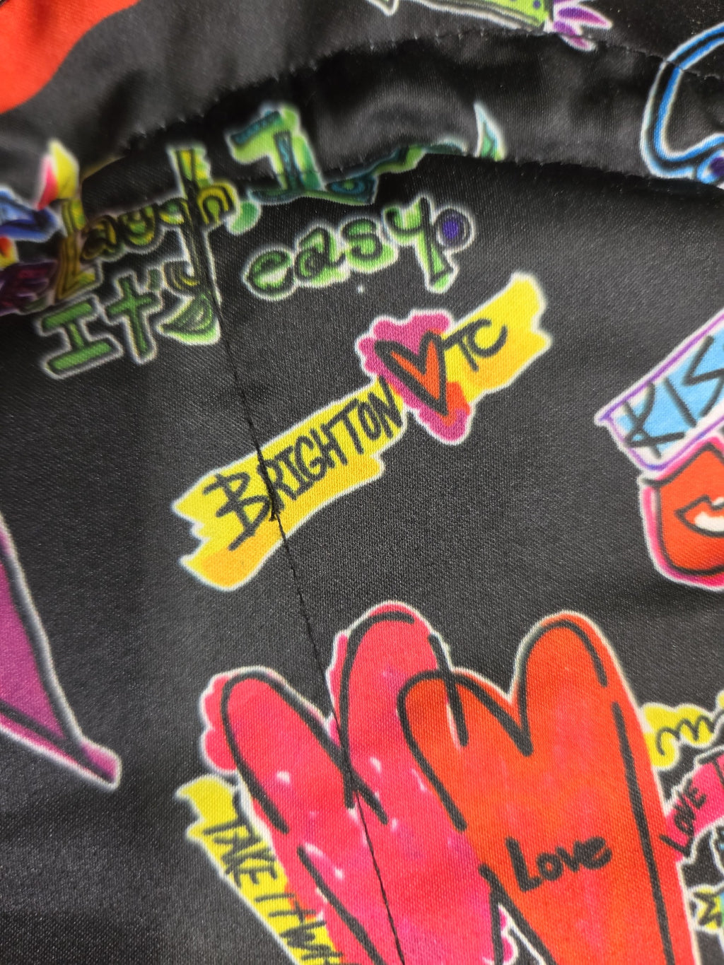 Oddly Darling Vintage Brighton drawstring pouch featuring a black satin fabric with colorful graffiti heart prints.