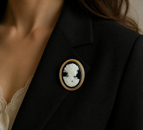 Oddly Darling Vintage cameo brooch with white portrait on black, gold rope frame, pinned on a black blazer lapel.