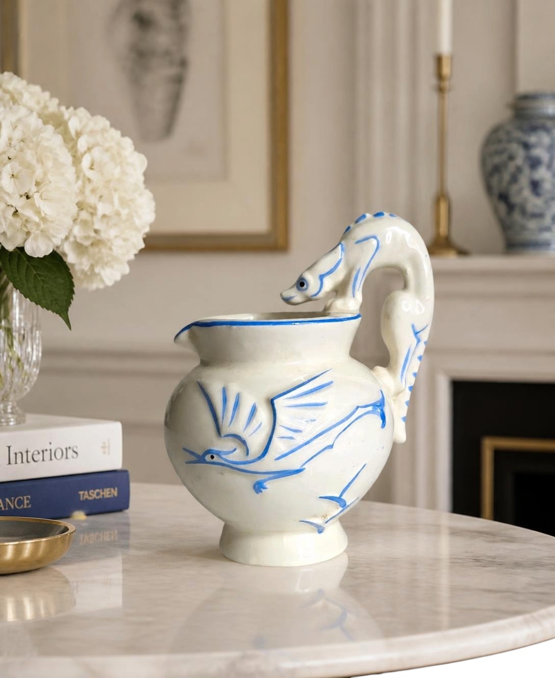 Oddly Darling Vintage ceramic pitcher with off-white glaze, cobalt blue bird motifs, and a sculptural animal handle.