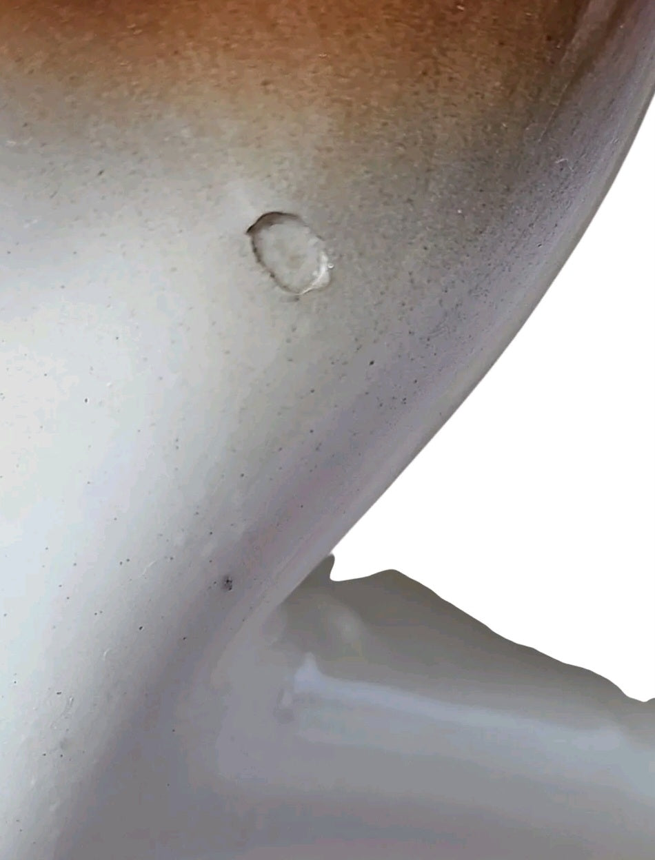 Close-up of a small chip on the glossy cream and brown ceramic surface of an Oddly Darling Vintage fawn figurine.