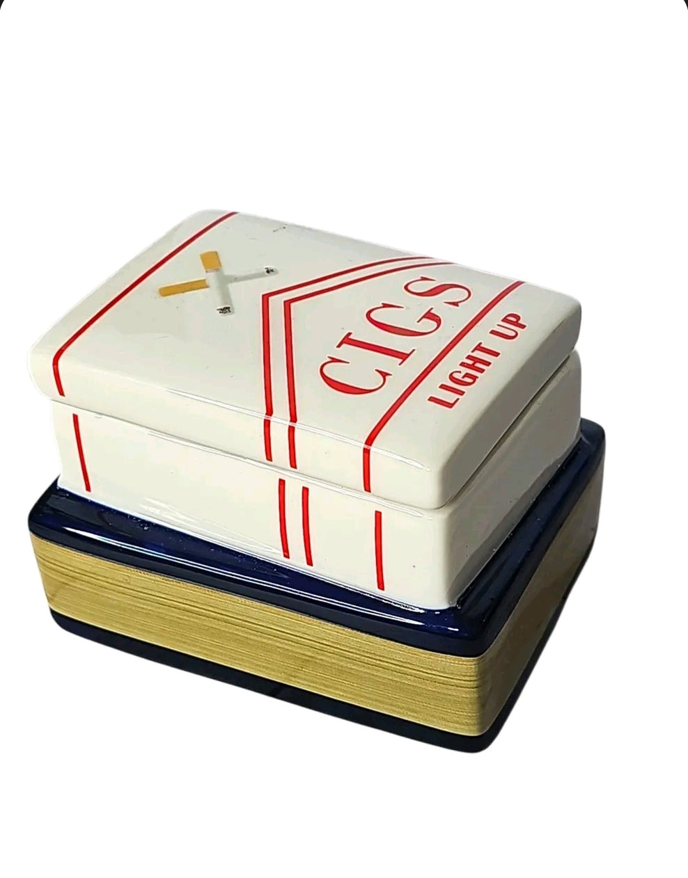 Oddly Darling Vintage ceramic trinket box shaped like a cigarette pack on a blue book with gold page details.