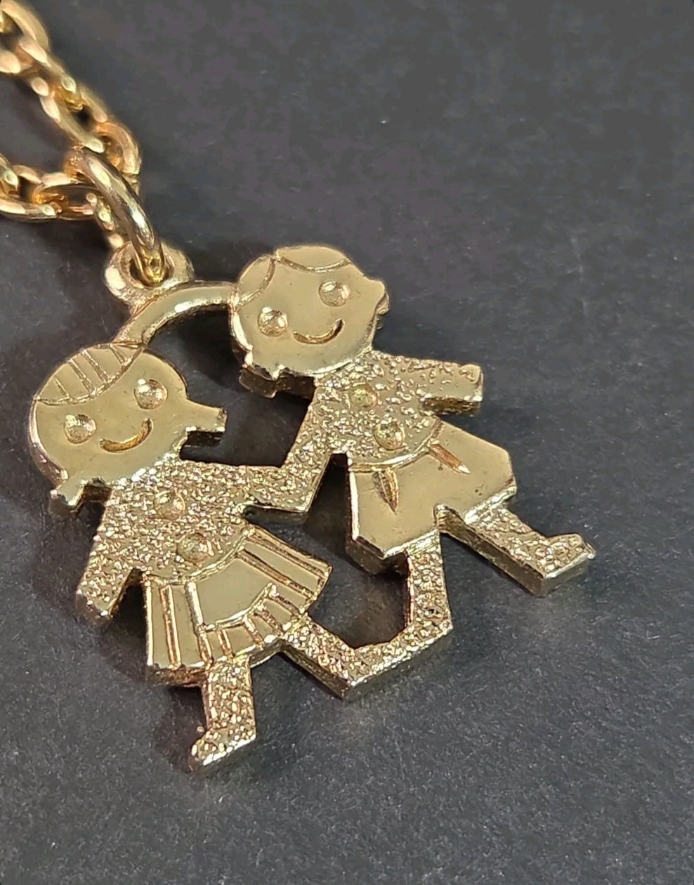 Oddly Darling Vintage gold-tone necklace featuring a textured pendant of two children holding hands on a link chain.