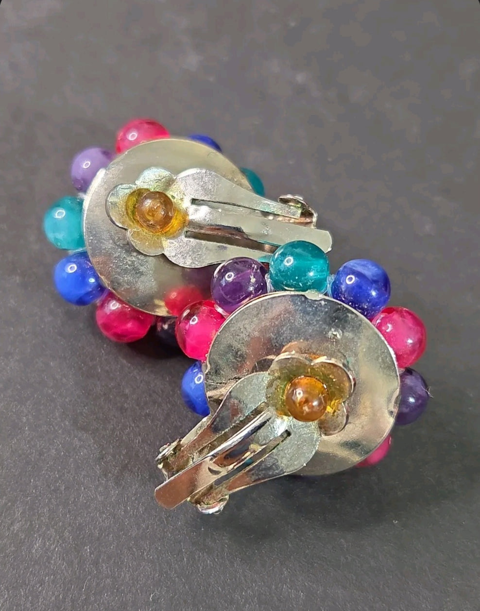 Oddly Darling Vintage multi-colored cluster bead clip-on earrings with silver-tone backings on a dark background.