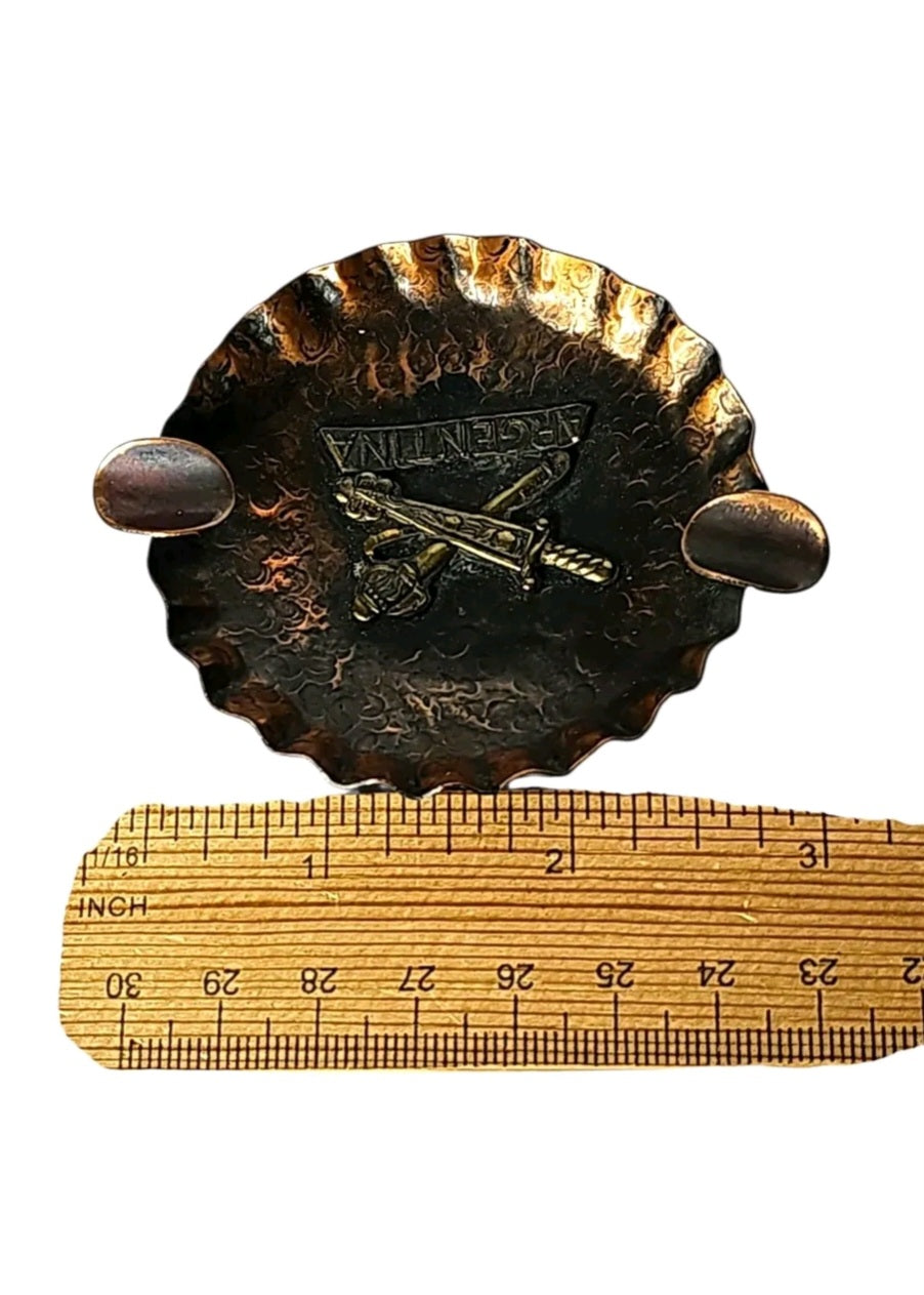 Oddly Darling Vintage hand-hammered copper ashtray with a brass Argentina emblem and crossed swords design.