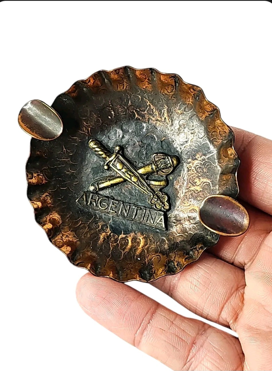 Oddly Darling Vintage hand-hammered copper ashtray with a brass Argentina emblem and crossed swords design.