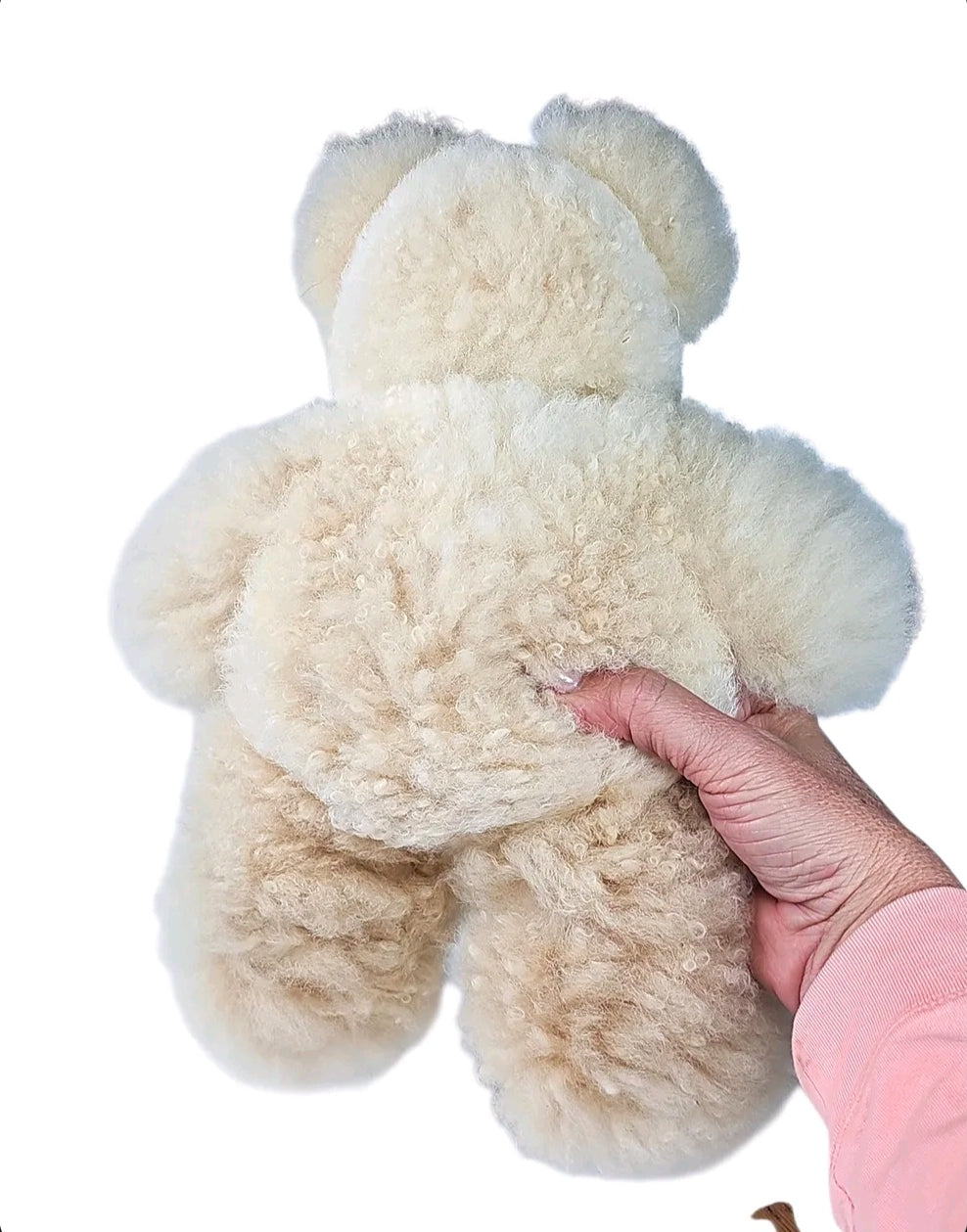Back of cream alpaca fur teddy bear held in hand showing soft curly fur