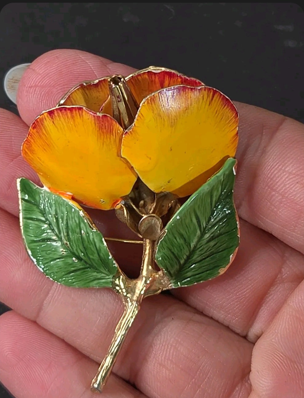 Oddly Darling Vintage floral brooch with yellow and orange enamel petals and green leaves on a gold-tone stem.
