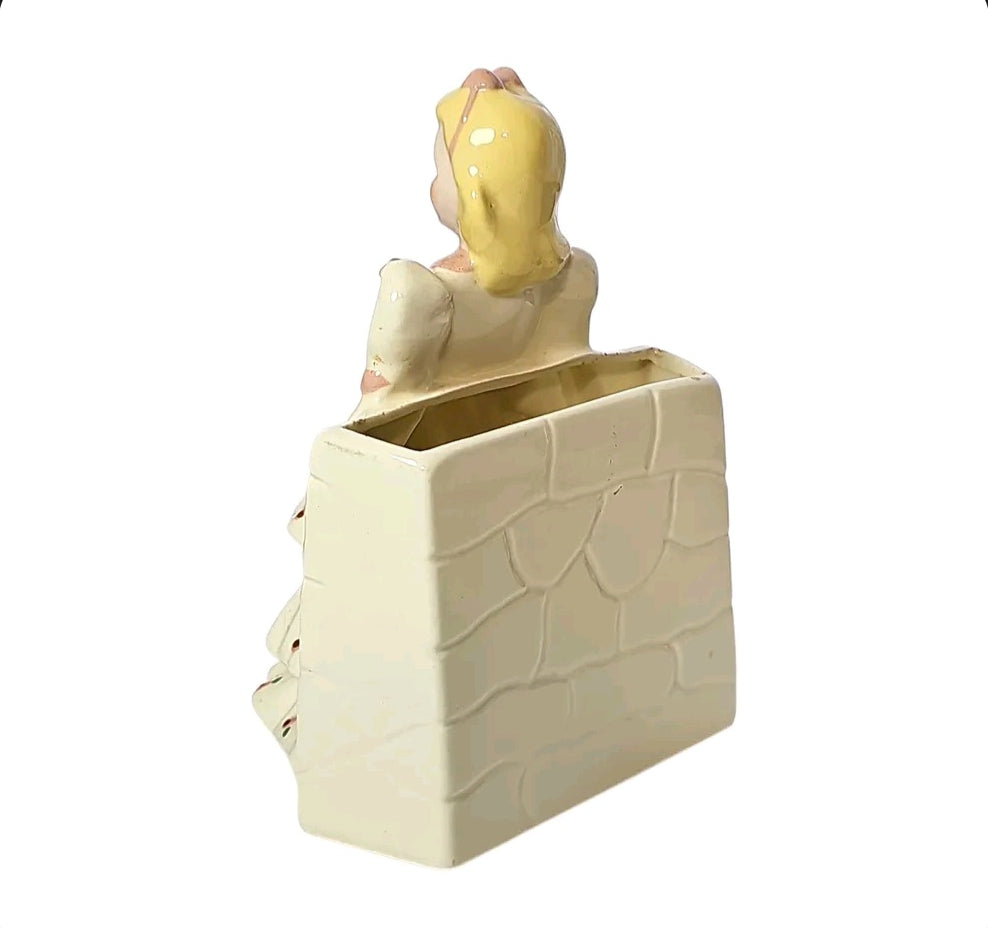 Back of vintage girl planter showing textured stone wall design