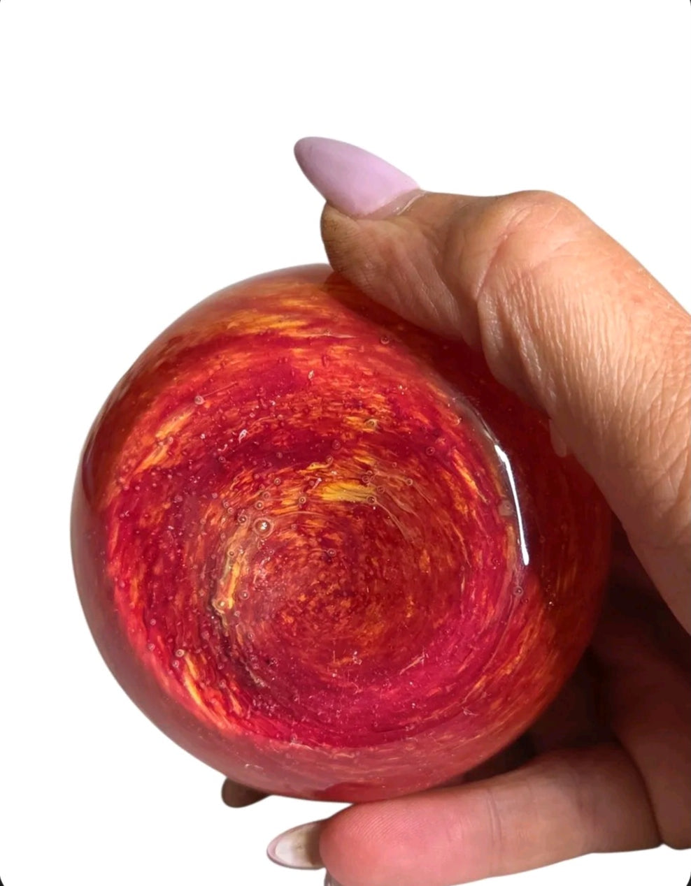 Oddly Darling Vintage hand blown glass fruit paperweight featuring a vibrant red and orange sunset swirl pattern.