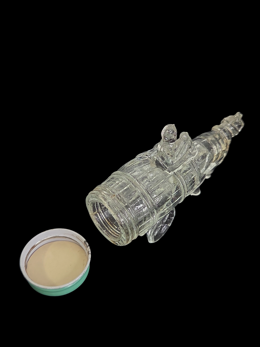 Oddly Darling Vintage clear glass horse and cart figural bottle with a light green screw-top lid on a black background.