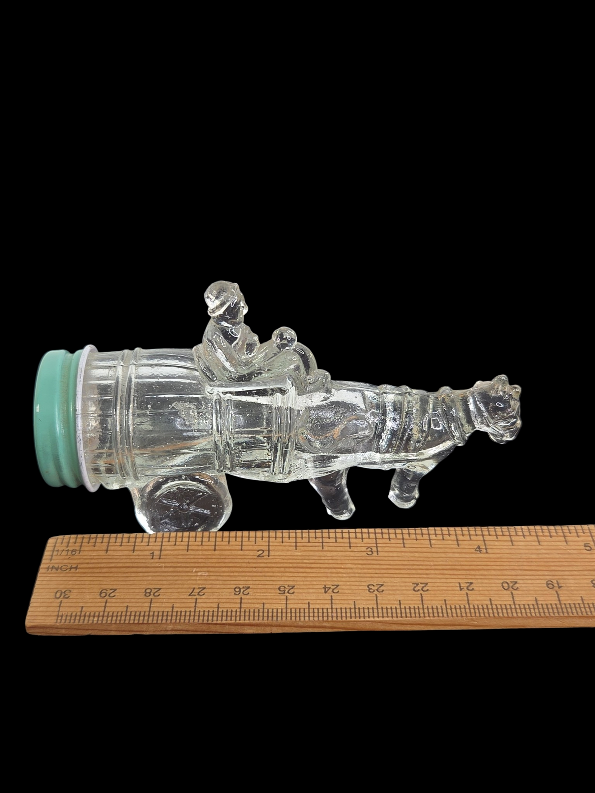 Oddly Darling Vintage clear glass horse and cart figural bottle with a light green screw-top lid on a black background.