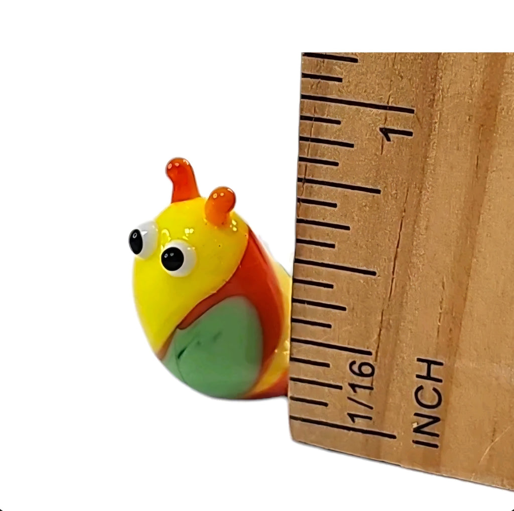 Oddly Darling Vintage handcrafted glass snail figurine in yellow, orange, and green next to a wooden ruler for scale.
