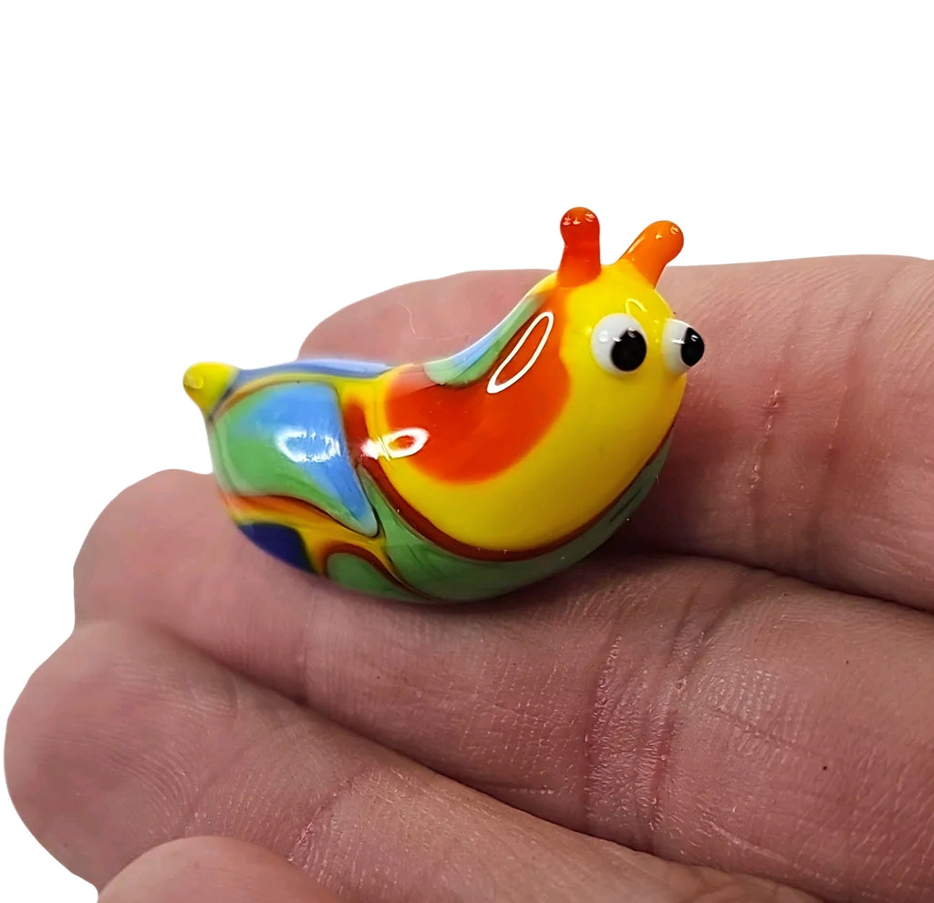 Oddly Darling Vintage handcrafted glass snail figurine in vibrant yellow, orange, blue, and green held in a palm.