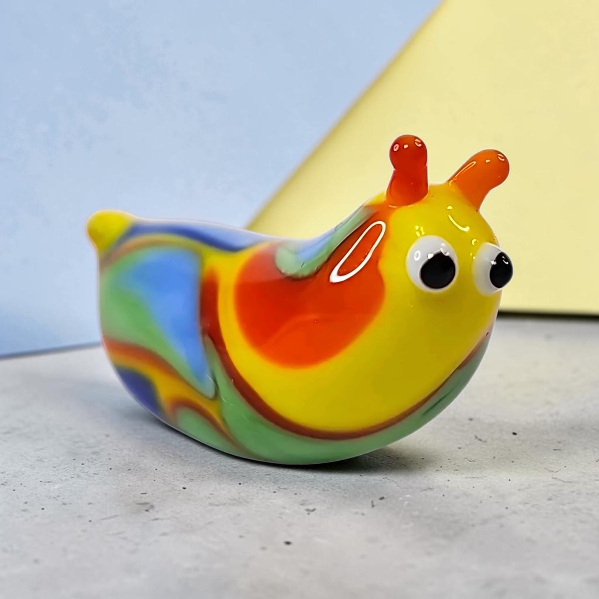 Oddly Darling Vintage handcrafted glass snail figurine with vibrant yellow, orange, blue, and green swirled patterns.
