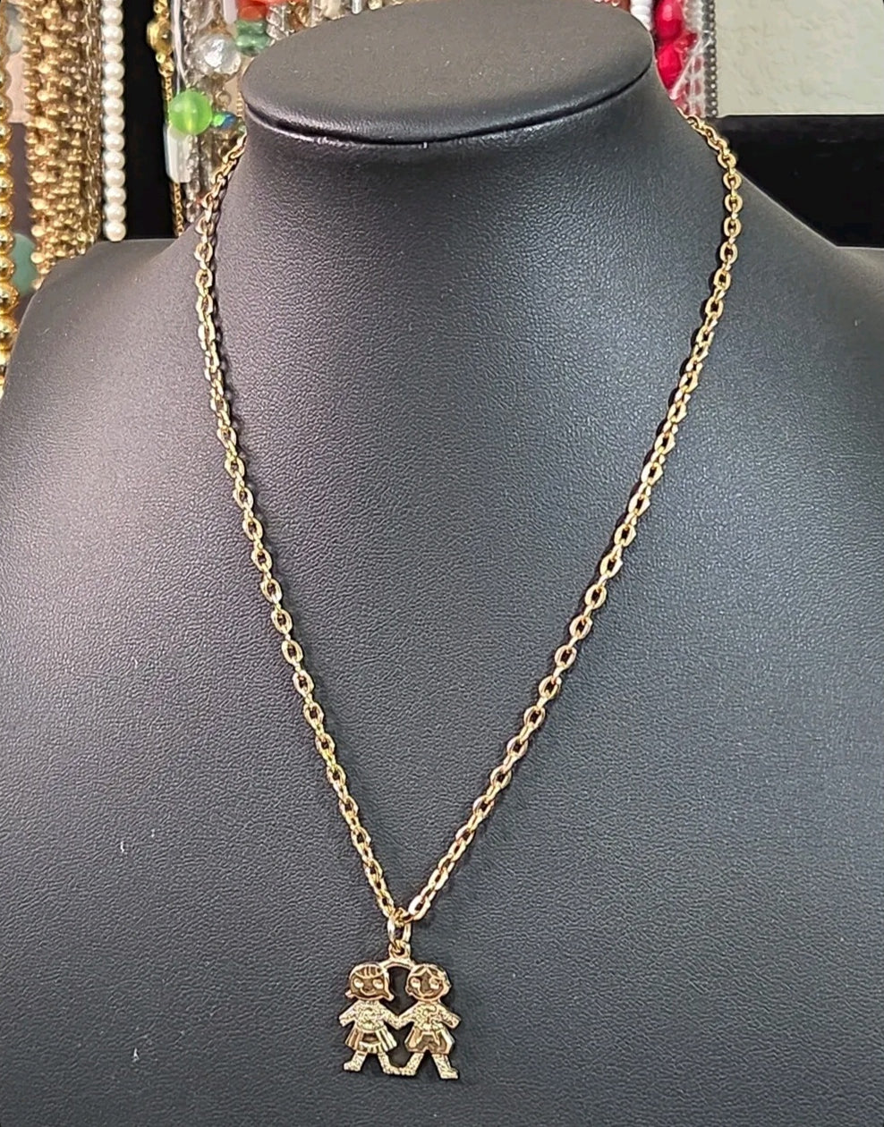 Oddly Darling Vintage gold-tone necklace featuring a pendant of two children holding hands on a delicate chain.