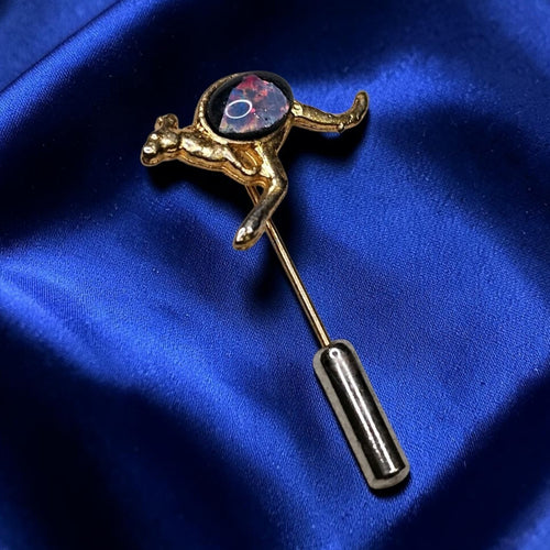 Oddly Darling Vintage gold-tone kangaroo lapel pin with a dark iridescent cabochon stone on a blue satin background.