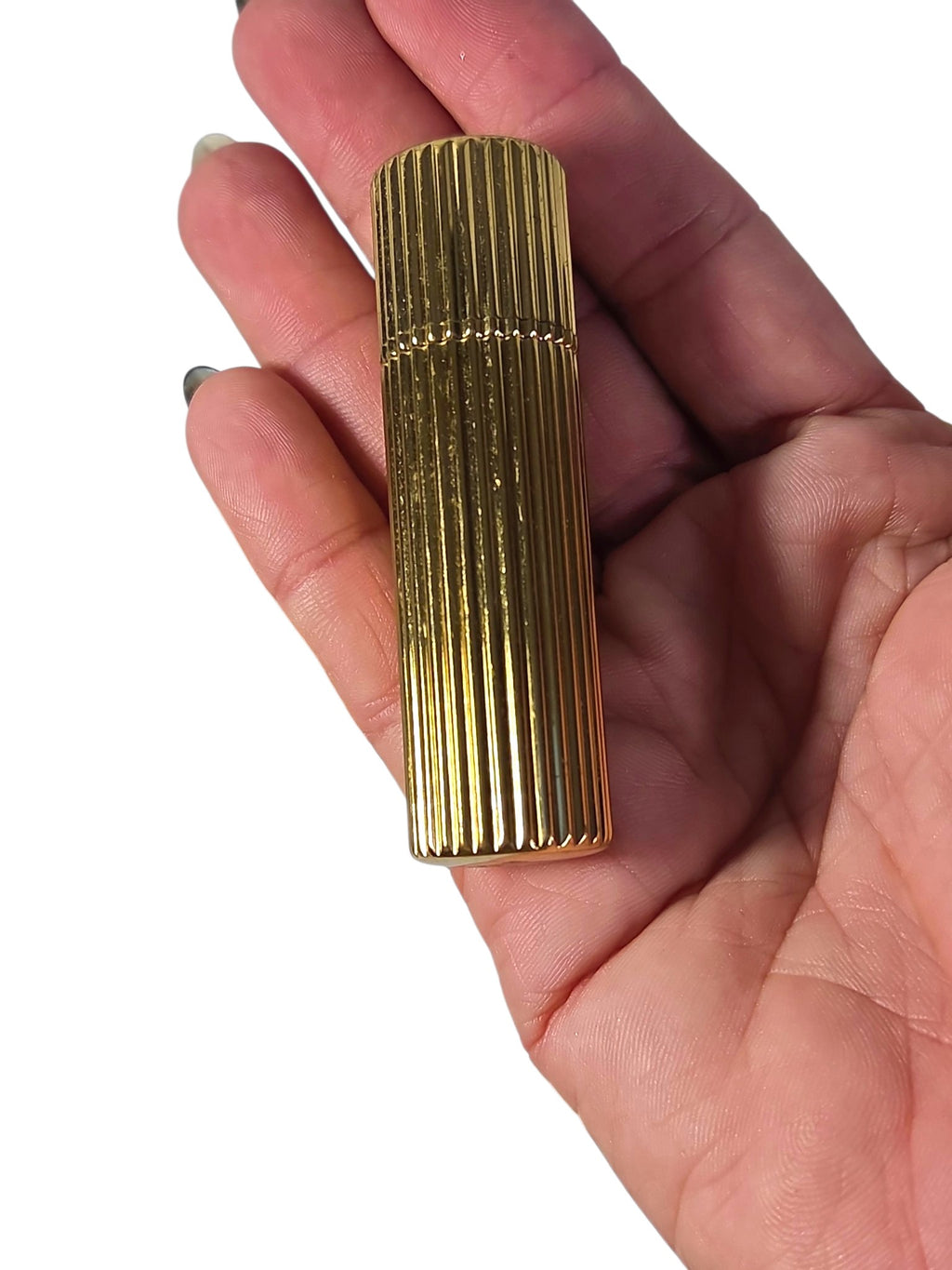 Ribbed gold-tone Estee Lauder lipstick case with cap on, held in palm