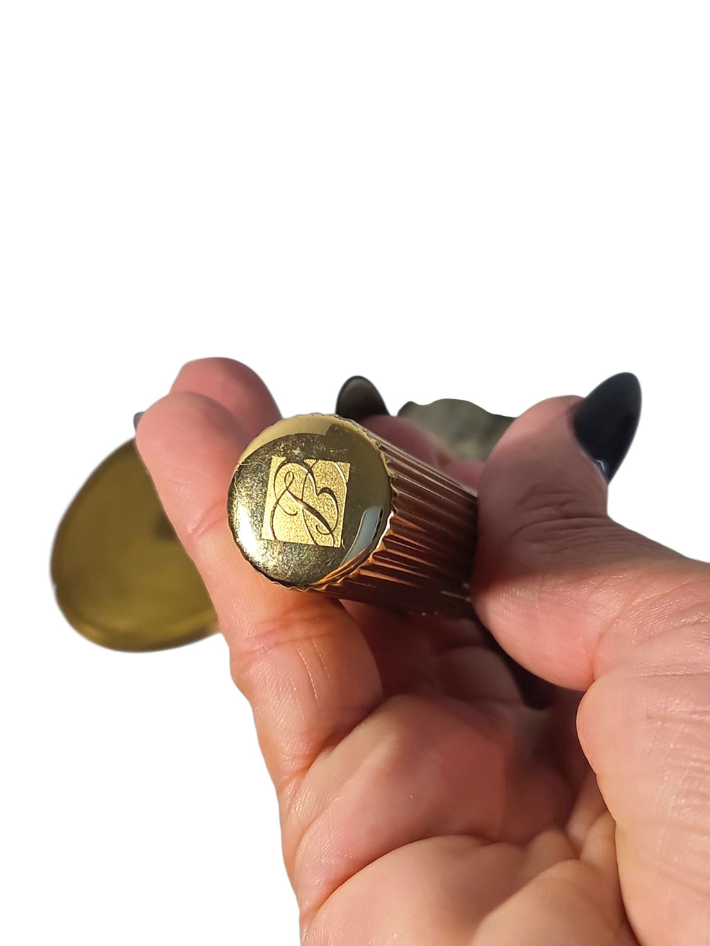 Estee Lauder lipstick cap with the engraved EL logo, ribbed gold-tone case held in hand