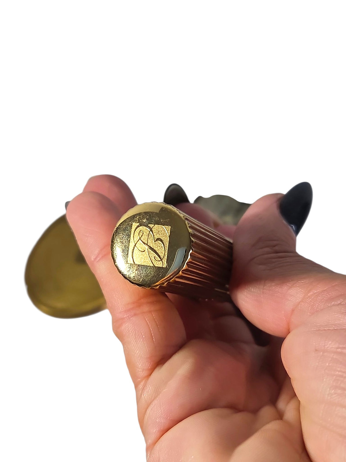 Estee Lauder lipstick cap with the engraved EL logo, ribbed gold-tone case held in hand