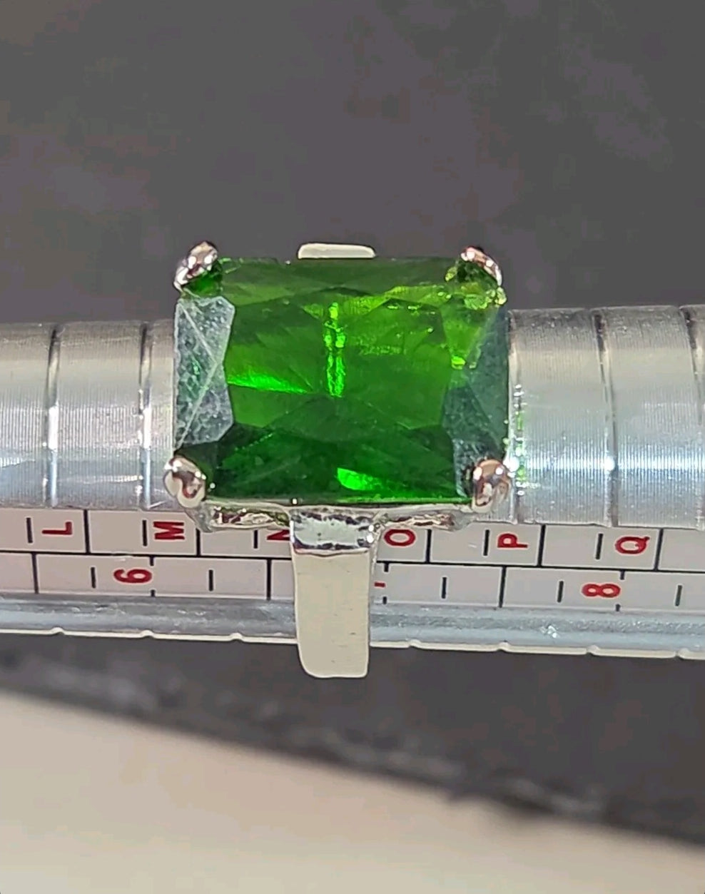 Oddly Darling Vintage emerald-cut green gemstone cocktail ring in a silver-tone four-prong setting on a ring sizer