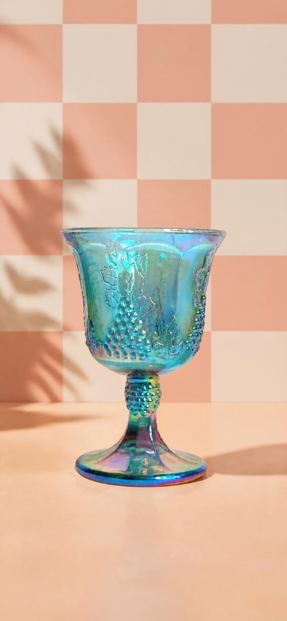 Oddly Darling Vintage iridescent blue carnival glass goblet with embossed grape and vine motif on a checkered background