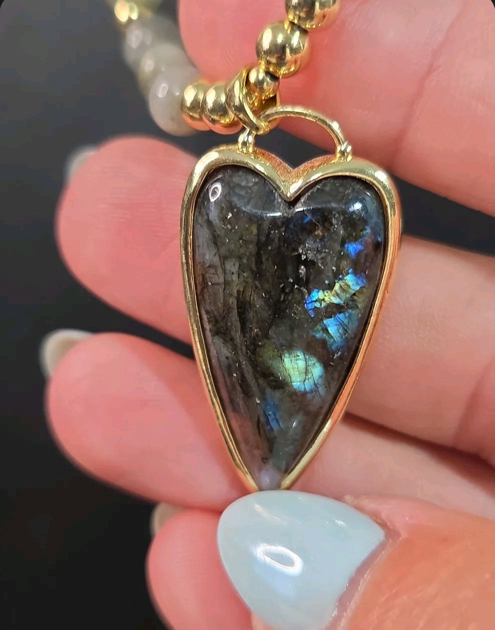 Oddly Darling Vintage heart-shaped Labradorite pendant necklace with gold-tone beads held in a hand.